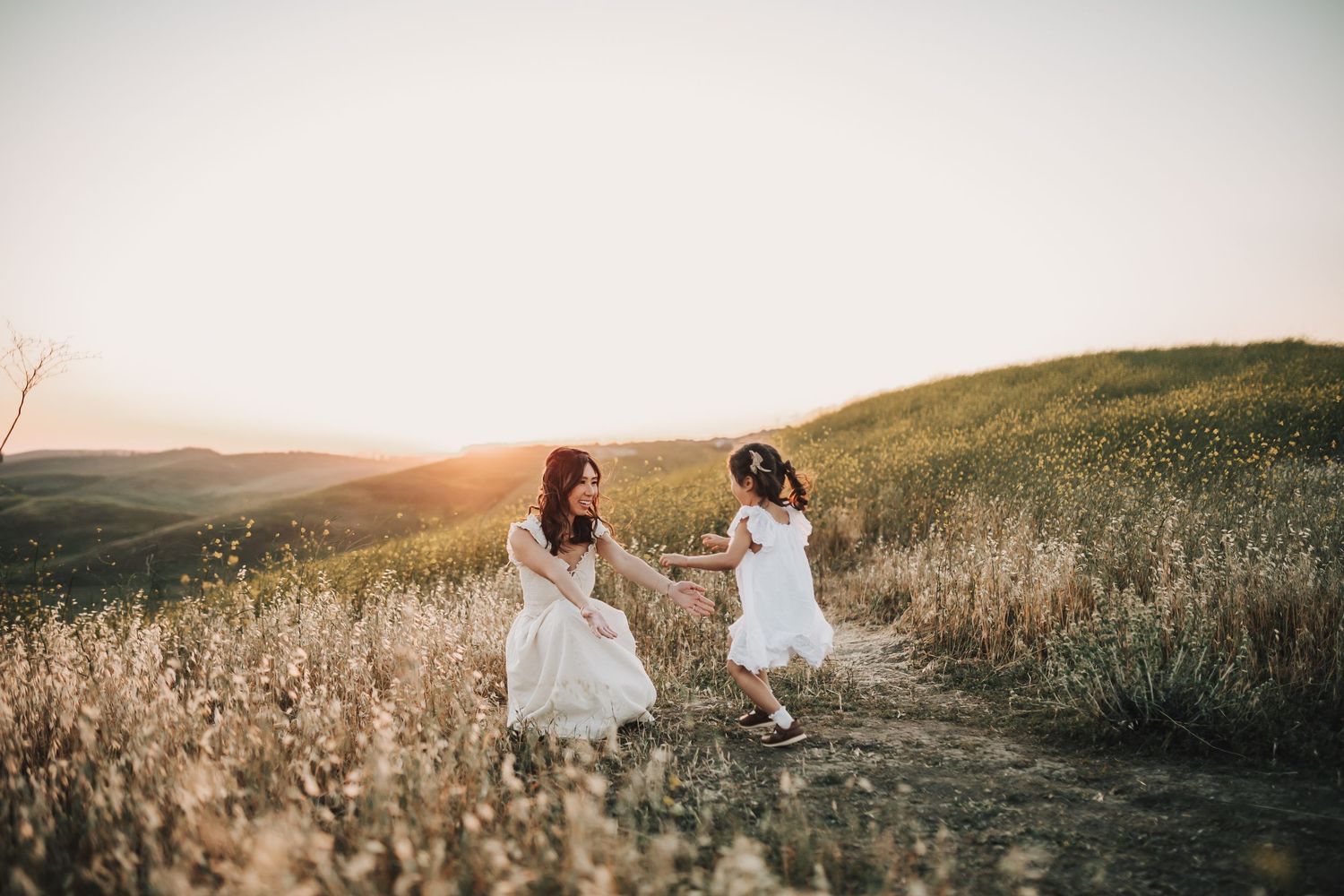 Family enjoying a warm sunset together in a meadow wearing coordinated casual outfits in light blue and grey tones.