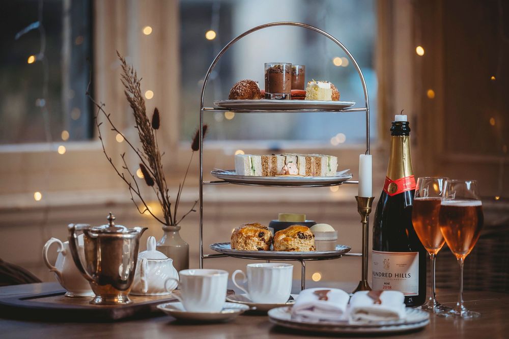 Elegant restaurant dinner table setting with soft lighting, wine glasses, and multi-tiered displays of desserts and appetizers.