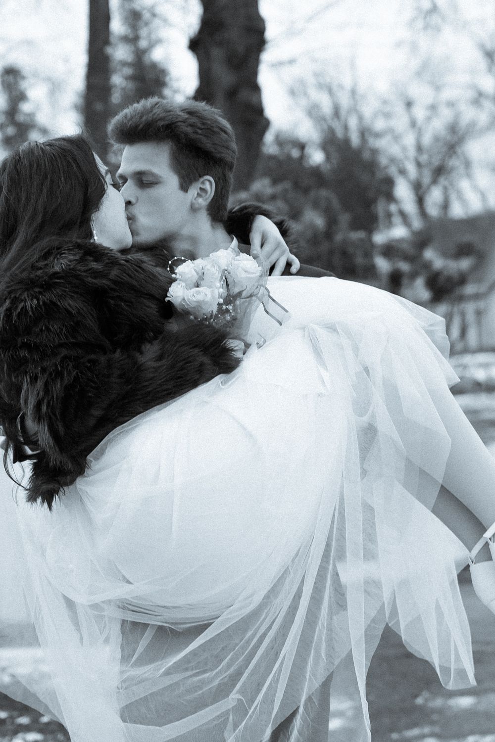 Romantic black and white photo of a couple in wedding attire sharing an intimate moment.