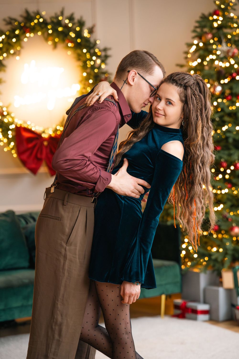 Sweet engagement moment captured in front of Christmas tree with warm holiday lighting.