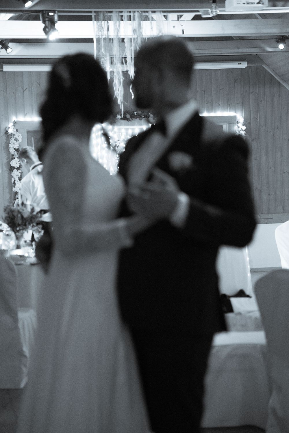 Blurred silhouette of dancing couple at wedding reception with decorative lighting.
