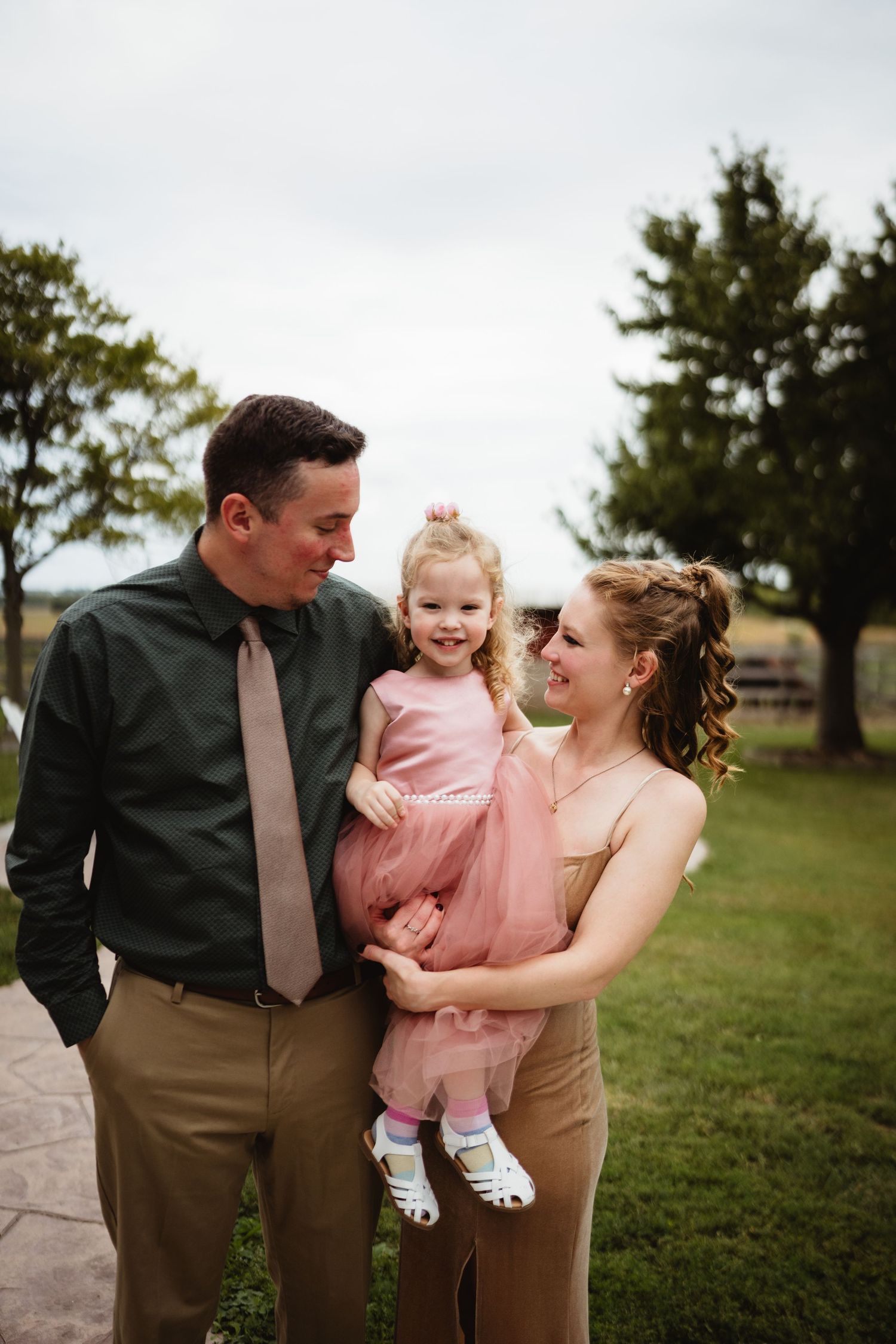 A loving family shares joyful moments together in a grassy outdoor setting at sunset.