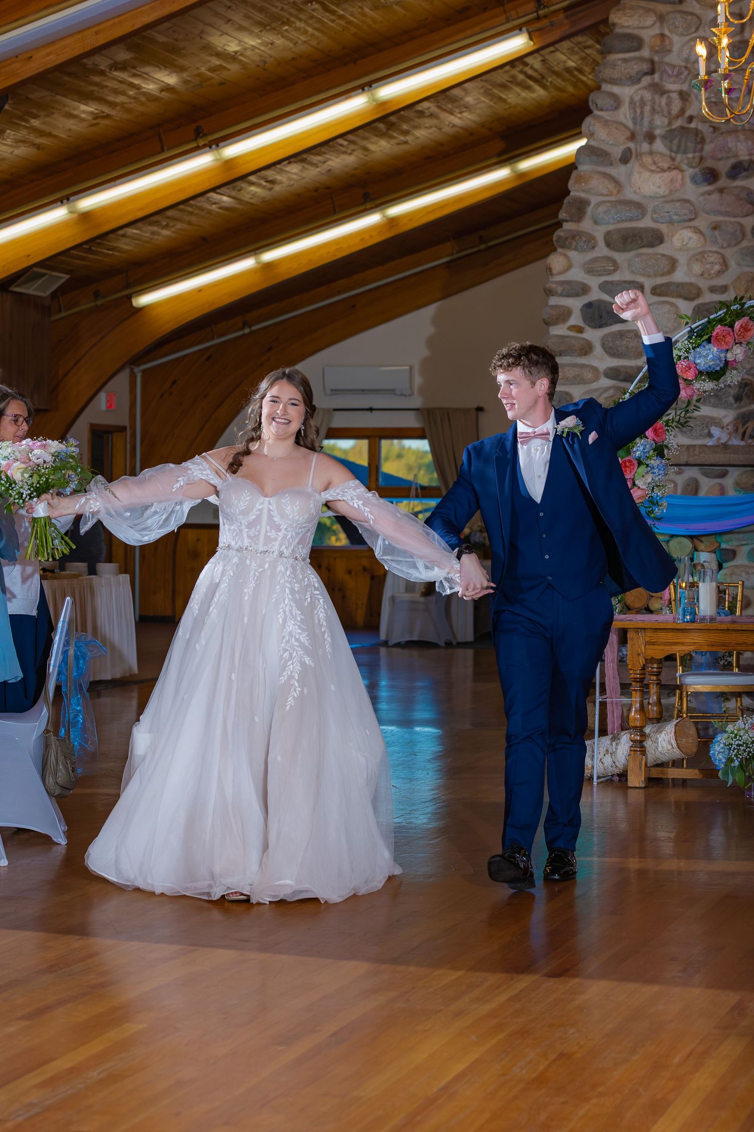 A couple dancing together in a rustic venue with wood floors and stone walls during a celebratory event.