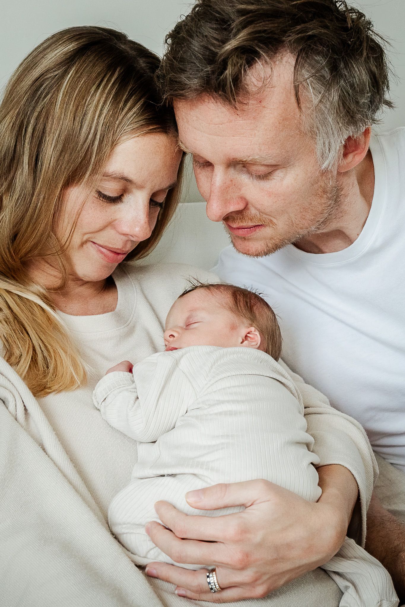 A mum and dad look natural and relaxed as they peer down at their sleeping newborn baby during their family photoshoot in Bristol