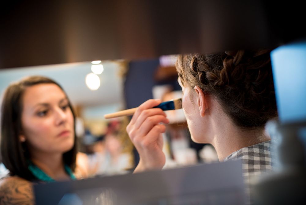 Makeup artist working on client in studio with soft lighting.