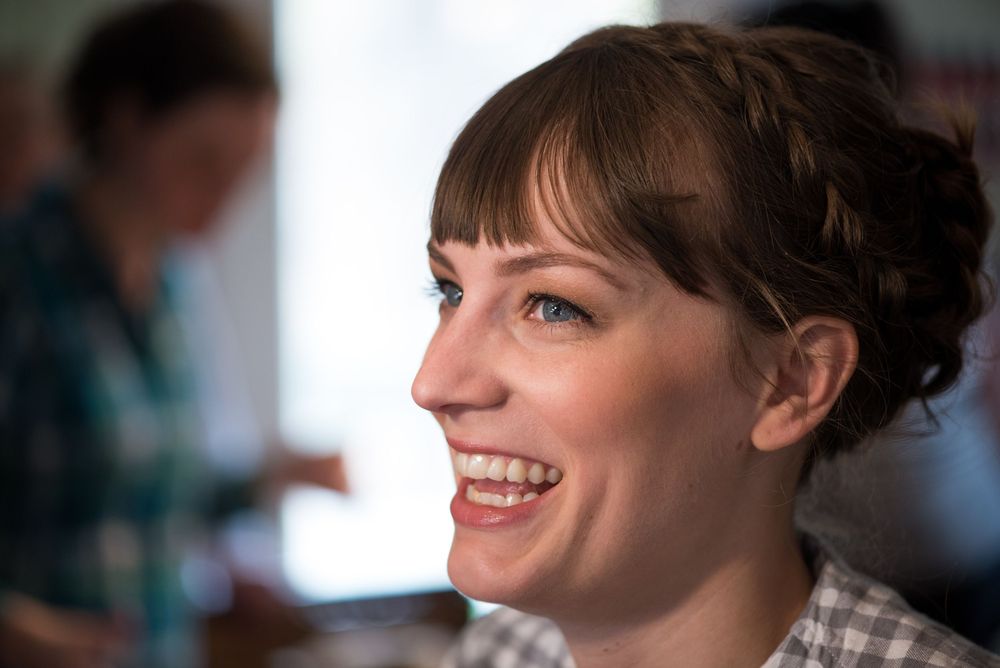 A candid portrait showing a warm smile and bangs hairstyle in natural lighting.
