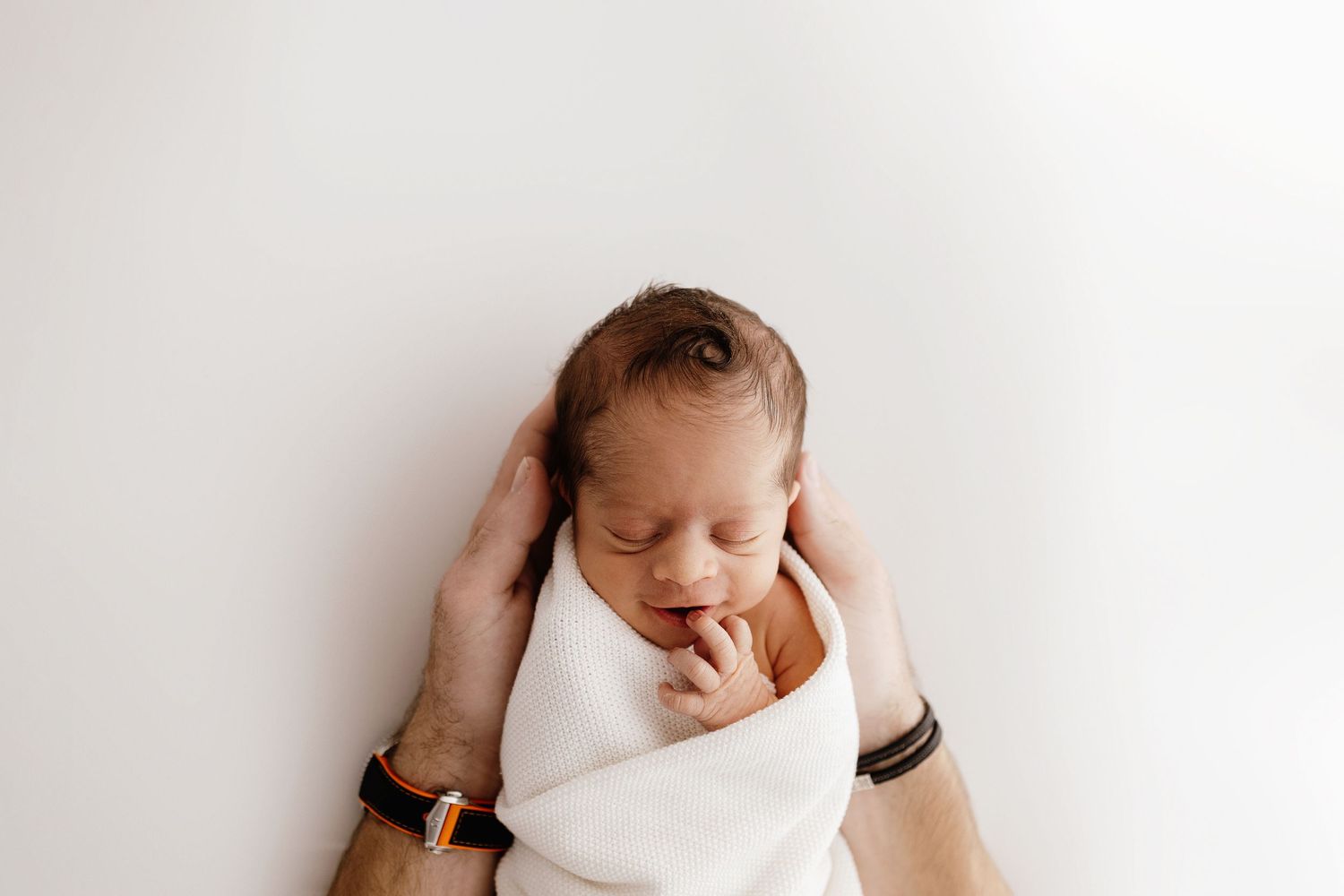 Minimalist newborn photography on white background with gentle lighting.