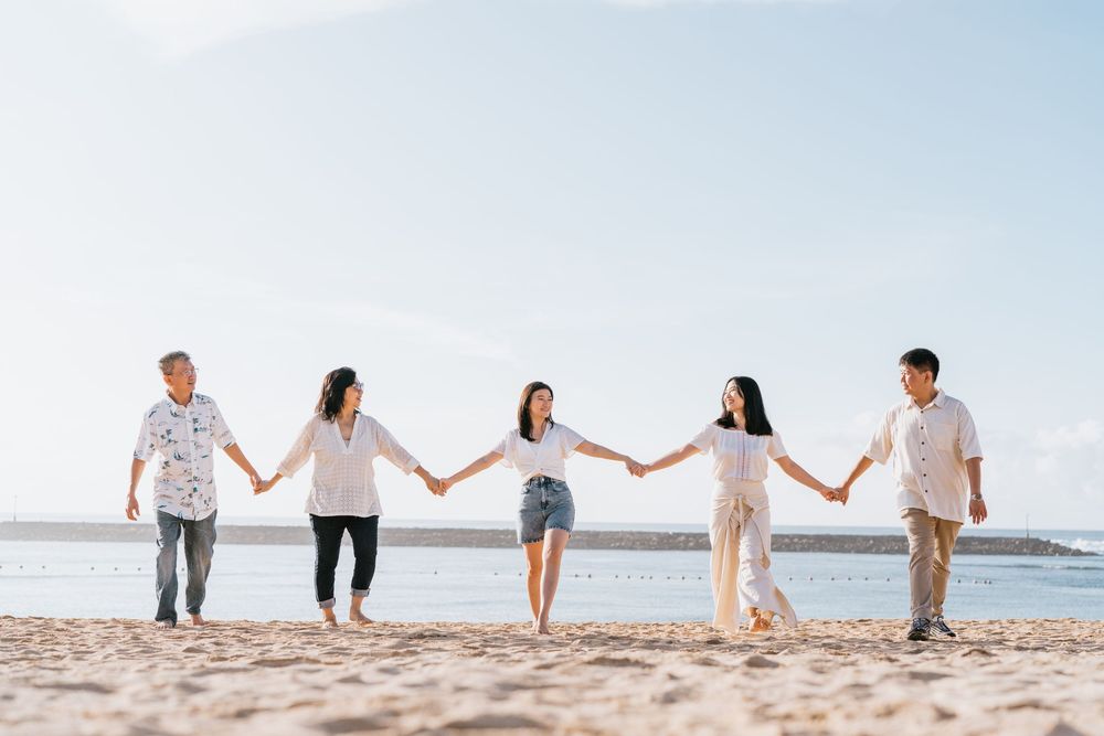 Row of people holding hands on beach during sunset photo session.