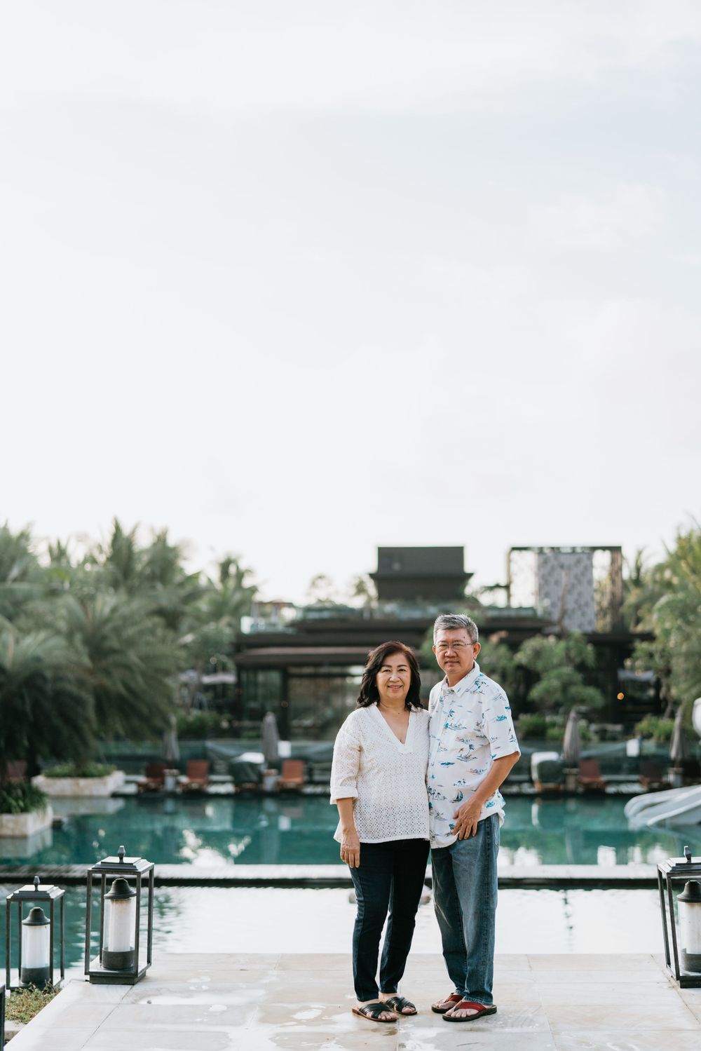 Couple strolling together near luxurious poolside setting with tropical landscaping.