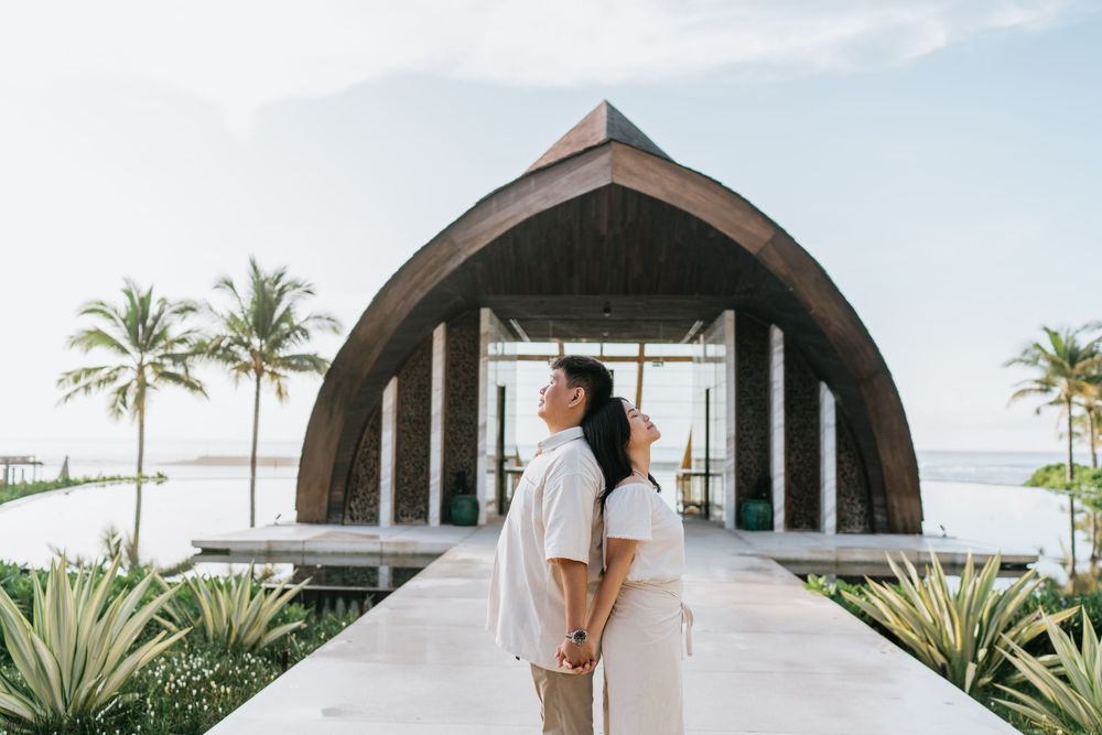 Modern resort architecture with curved dome structures against a bright sky and palm trees.