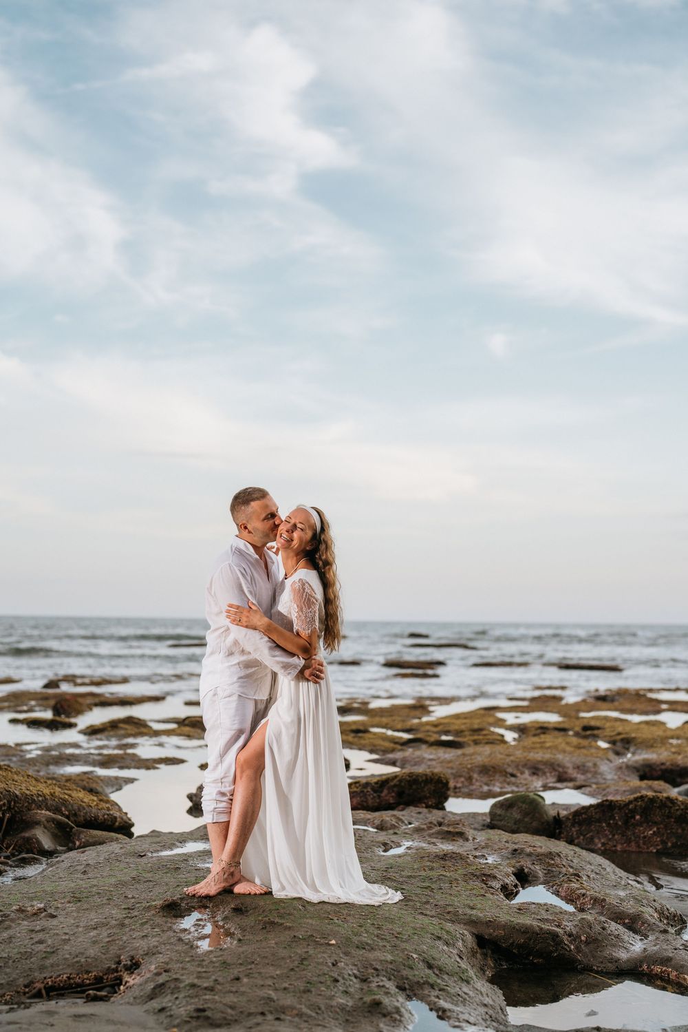 A romantic coastal portrait with waves and rocky shoreline during golden hour.