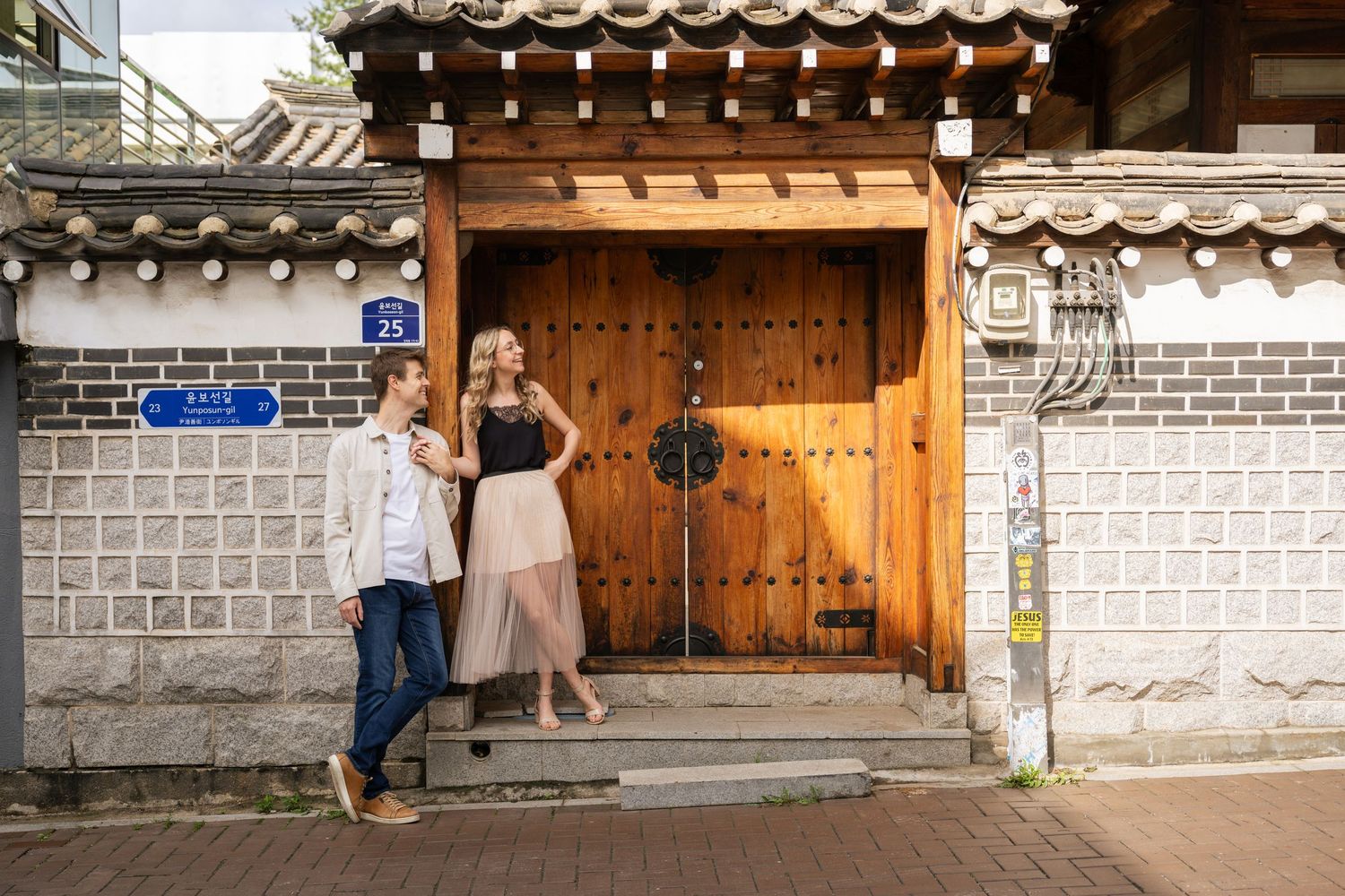 Traditional Korean hanok architecture with stone walls and wooden gates in an urban setting.