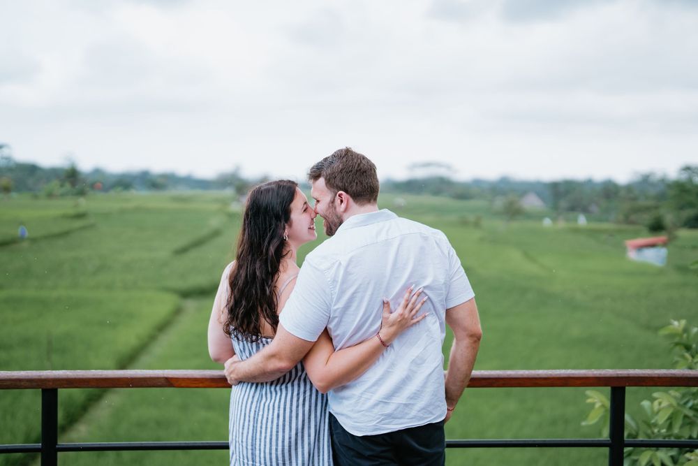 Couple embracing on balcony overlooking lush green rice terraces.