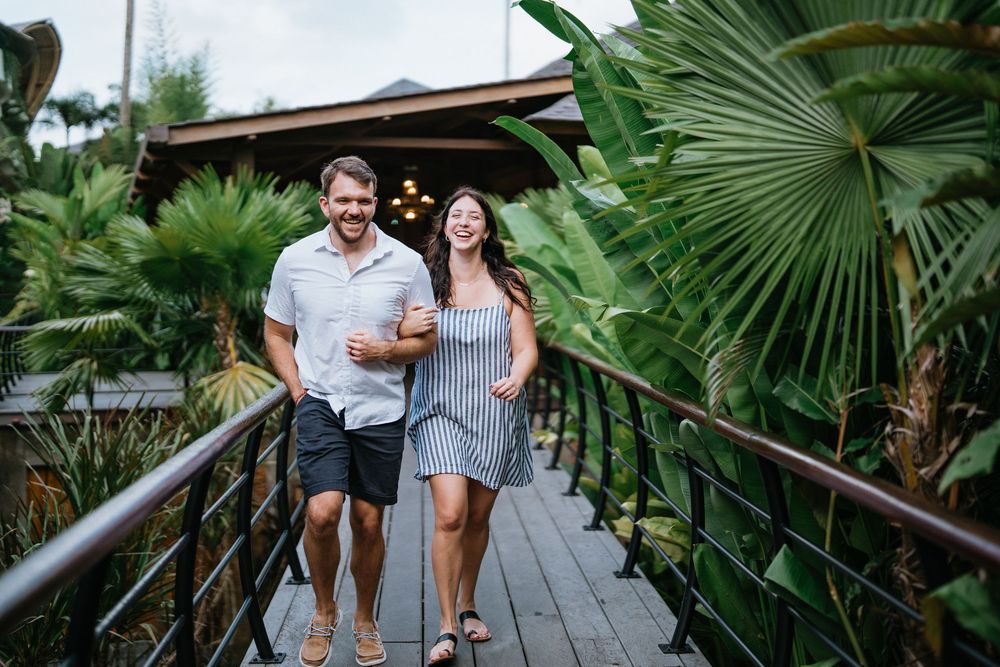 A couple shares a moment on a wooden walkway surrounded by tropical palm fronds.