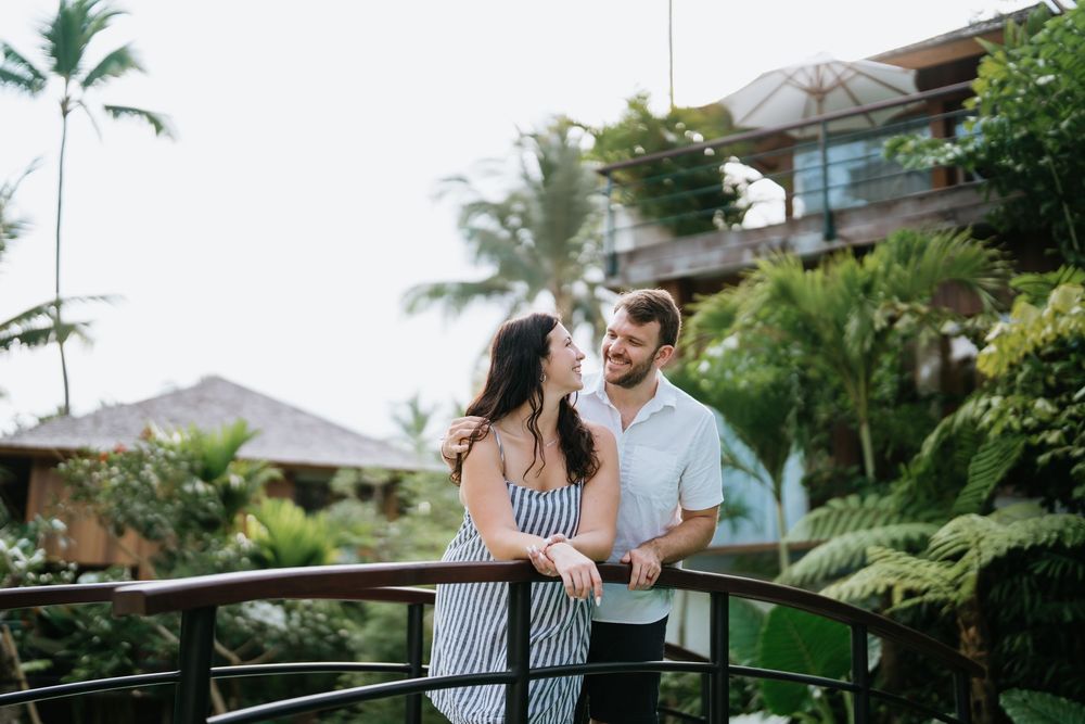 A couple enjoys a tender moment among palm trees and tropical landscaping.