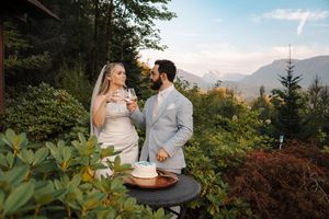 Couple enjoys sunset picnic with wine and charcuterie board on rustic wooden table in mountain setting.