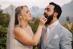 Wedding couple stands closely together outdoors laughing with mountains in the background during golden hour.