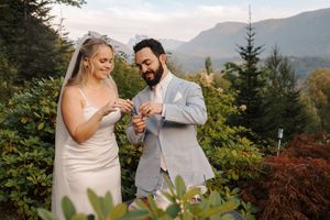 Couple celebrates intimate outdoor wedding ceremony in mountain setting among evergreen trees and autumn foliage.