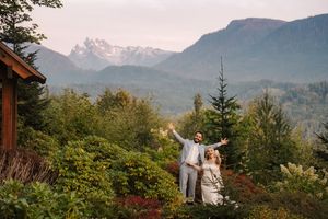 A romantic mountain wedding ceremony set against a backdrop of misty peaks and evergreen forests at sunset.