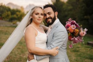 A joyful wedding couple shares intimate moments outdoors during their autumn ceremony with floral bouquet details.