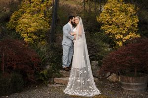 A couple embraces surrounded by vibrant autumn foliage during their outdoor wedding photoshoot.