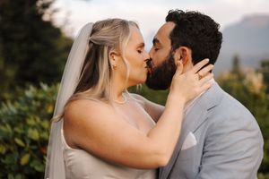 A romantic moment captured between a bride and groom in an outdoor garden setting with mountains in the background.