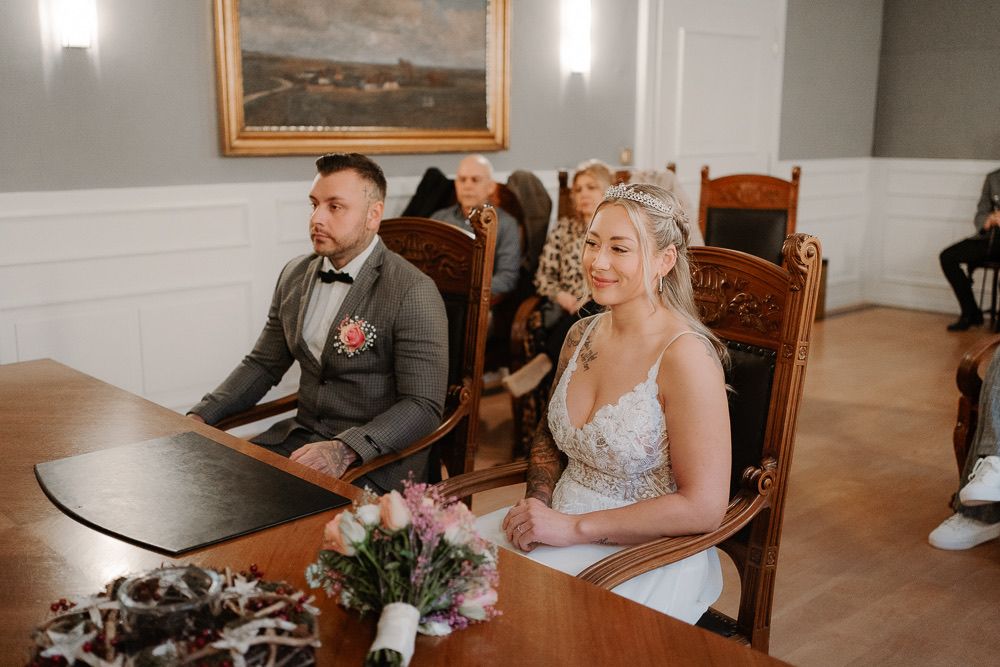 Wedding party members sit together in a rustic indoor venue with warm lighting and elegant decor.