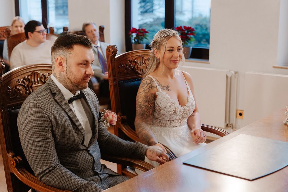 A couple signs their marriage license at a table while surrounded by loved ones during an intimate wedding ceremony.