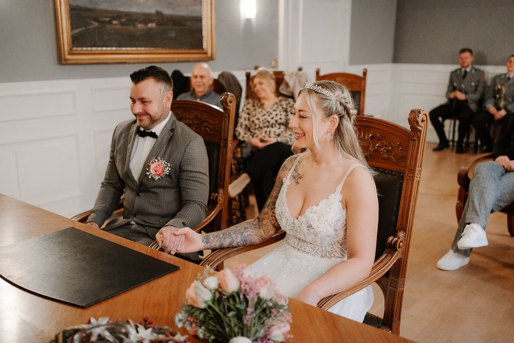 People seated at a formal table with floral centerpiece in an elegant meeting room setting.