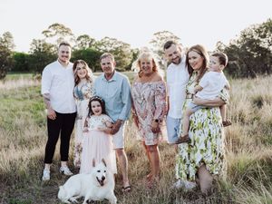 Extended family gathering in casual attire posed together in a natural outdoor setting.