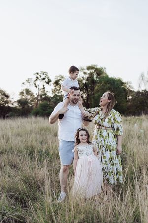 Casual family portraits taken in a field of tall grass during golden hour.