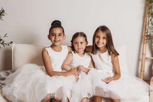 Group photo of children wearing coordinating white outfits against neutral background.