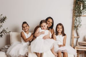 A series of coordinated family photos showing a group in white outfits against neutral backgrounds.