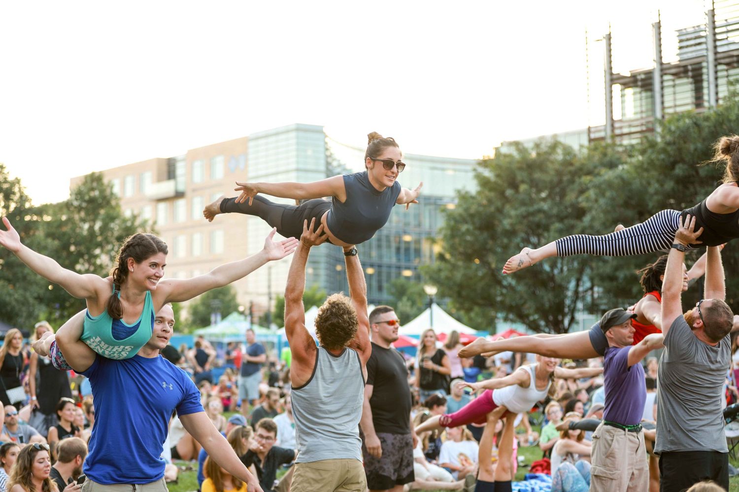 Acrobatic performers demonstrate impressive balancing acts at an outdoor festival with a crowd of onlookers.