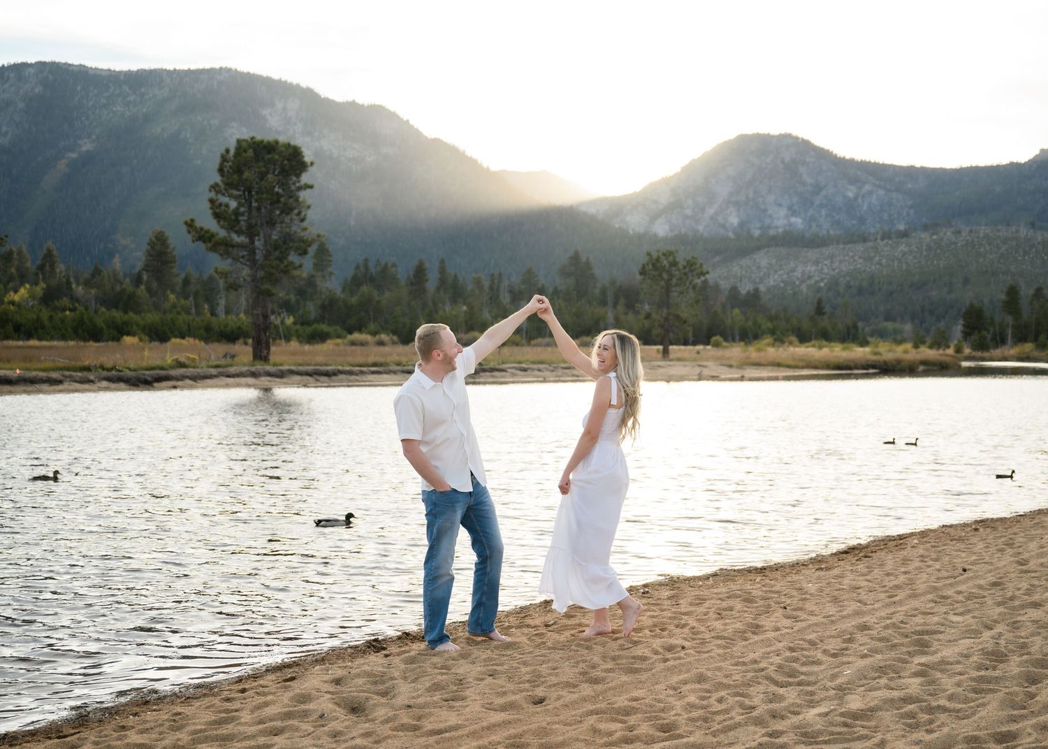 A photo of a bride to be and a groom to be dancing and laughing during an engagement session in South Lake Tahoe in Northern California.