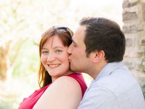 A couple shares an intimate moment outdoors as they embrace and smile in the warm sunlight.