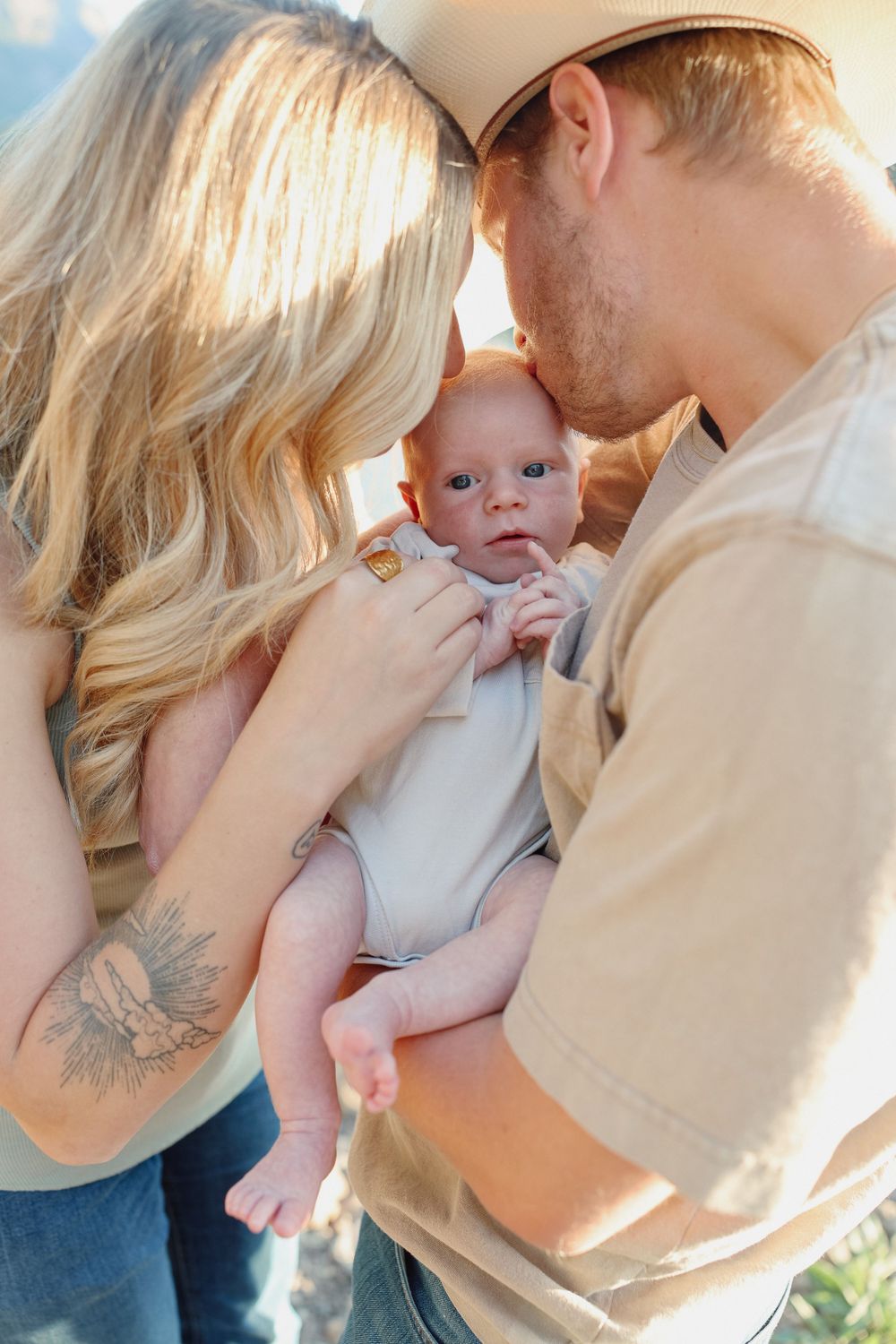 parents kissing their newborn baby