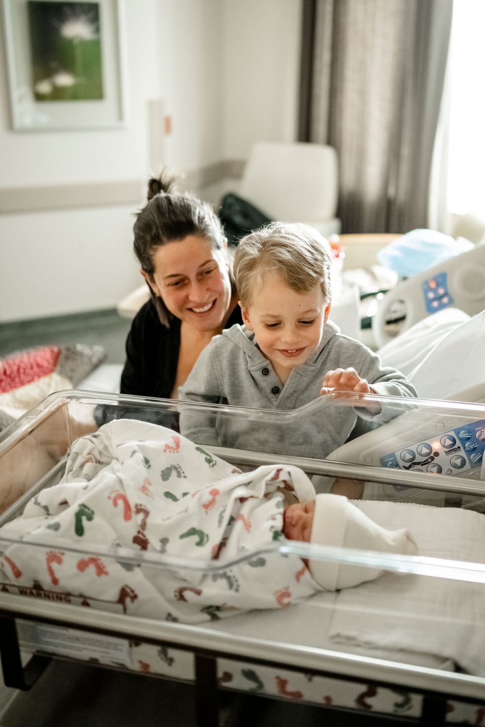 A heartwarming scene in a hospital room with a newborn in a clear bassinet.