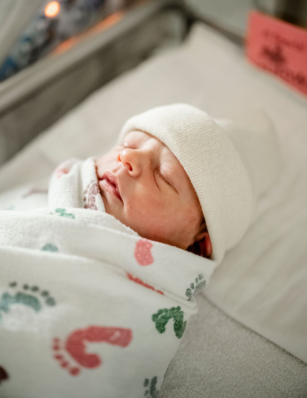 Newborn baby sleeping peacefully wrapped in a blanket with footprint designs.
