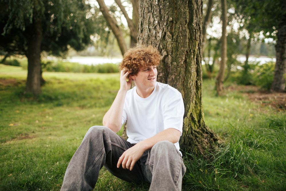 A teenager looks away from the camera at a park in Silverlake Everett WA during his Senior photo session in the summer
