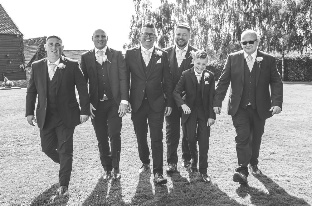 Groomsmen walking together outdoors in black and white photography.