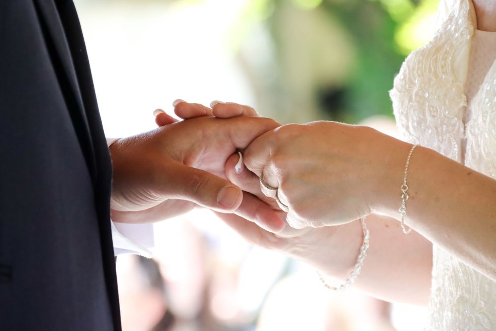 Close-up of hands joining together during wedding ceremony.