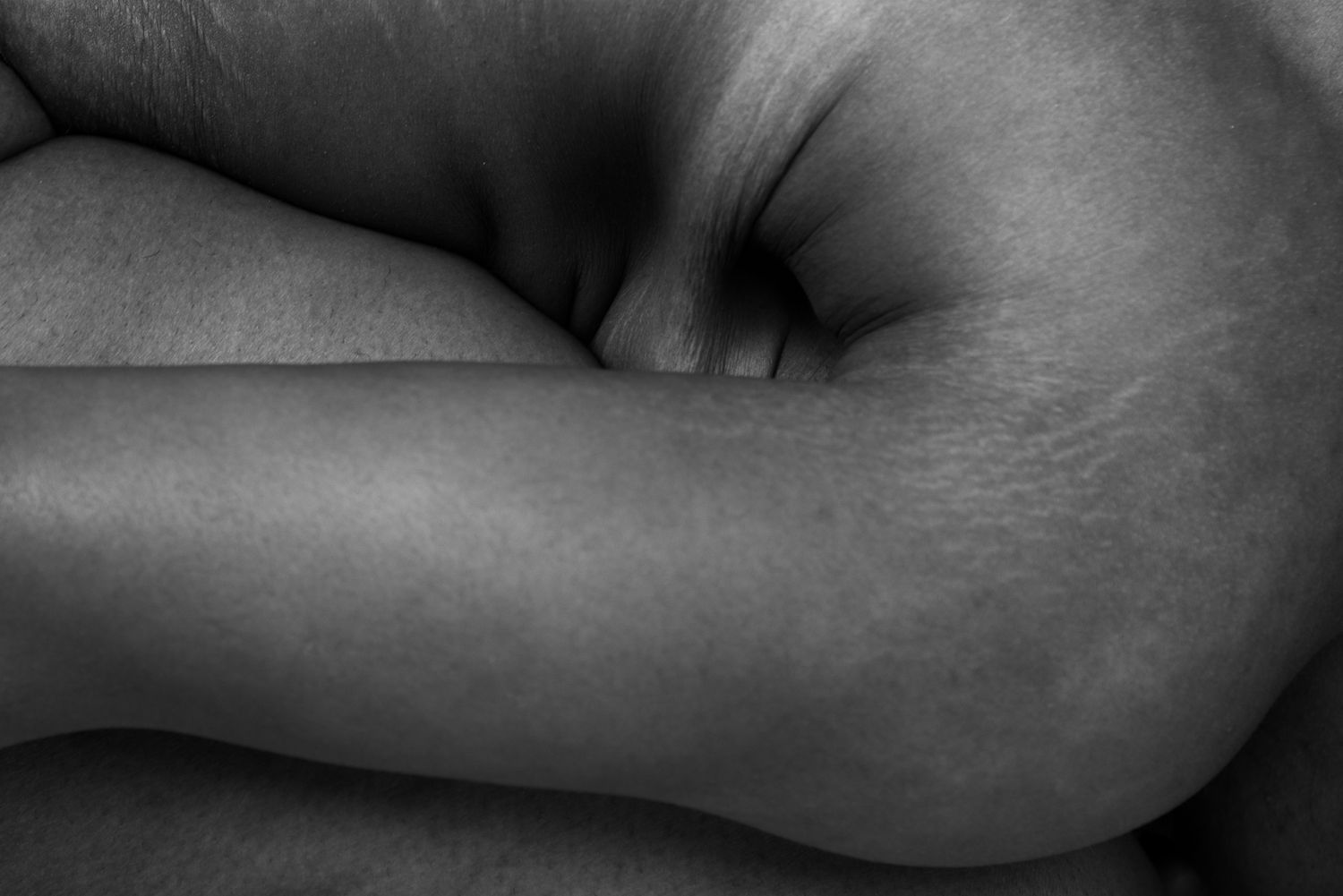Abstract black and white close-up study of curved body forms and shadows.