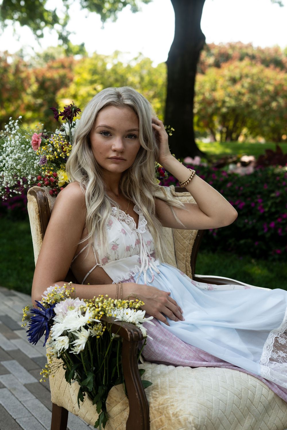 Dreamy outdoor portrait series featuring elegant white dress and floral arrangements in a garden setting.