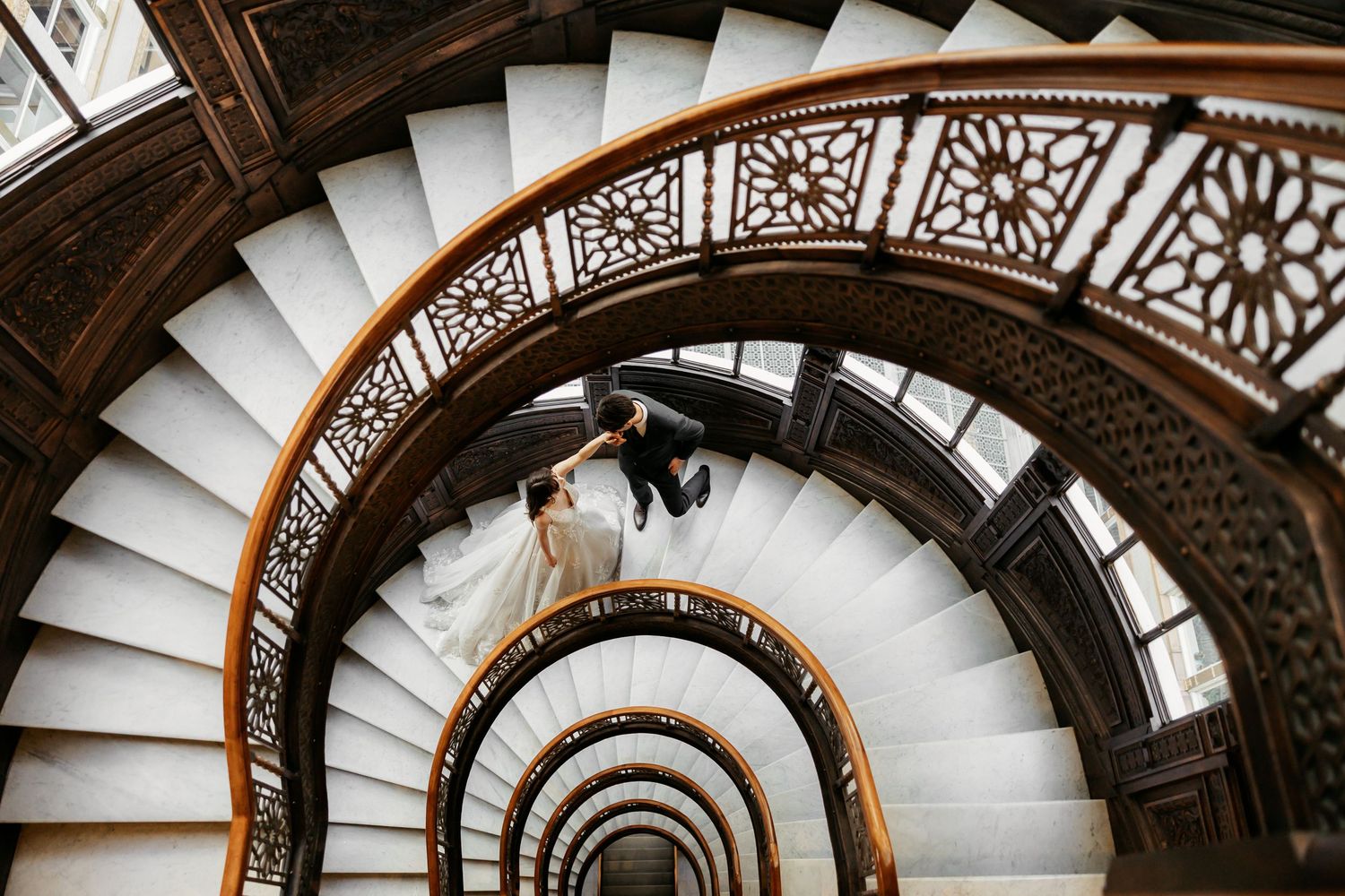 Bride and groom cuddling on the stairs of the rookery in chicago, Illinois.