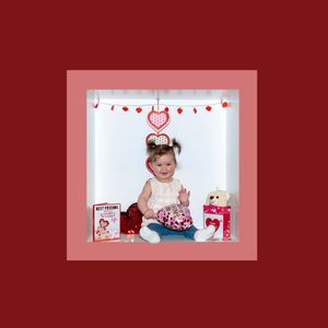 Valentine's day themed photo session with red backdrop, heart decorations, and festive props for children's portraits.