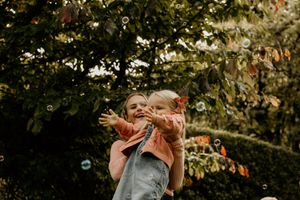 Joyful moment captured outdoors with bubbles and autumn foliage.