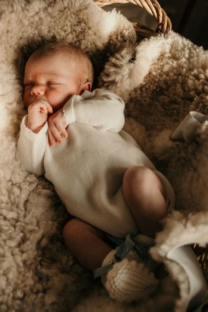 A baby sleeps peacefully nestled in soft white cotton while lying on fluffy cotton bedding.