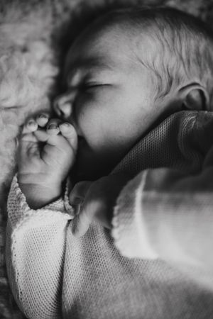 A series of black and white photos showing a sleeping baby in a textured blanket or fabric.