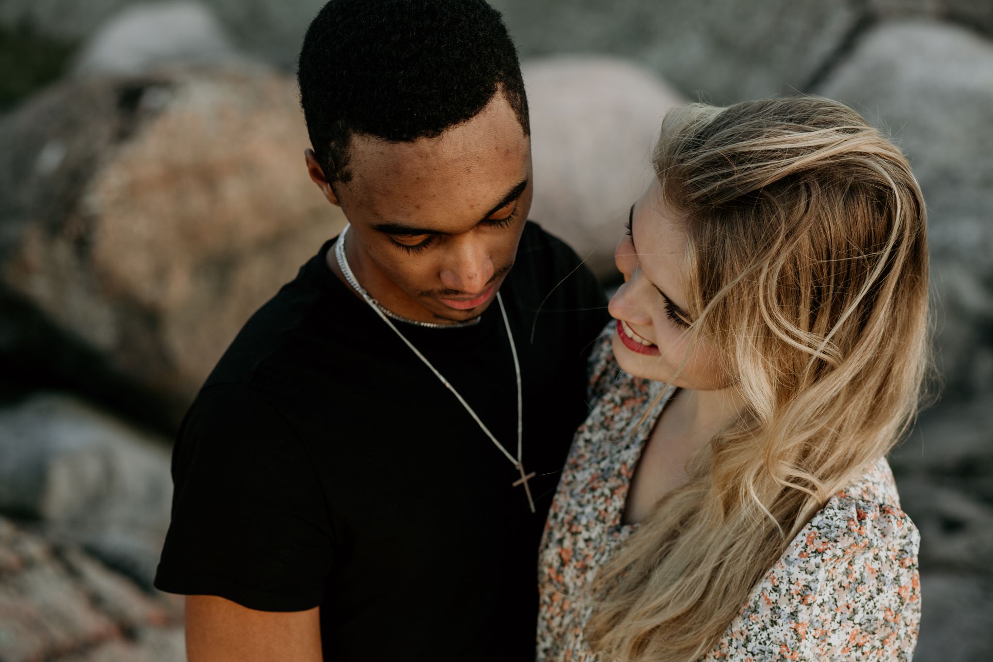 Intimate couple portrait against rocky backdrop in casual attire.